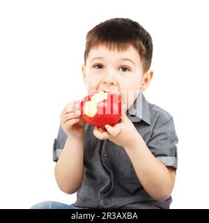 Close-up portrait of a little boy eating red apple isolated on white background Stock Photo