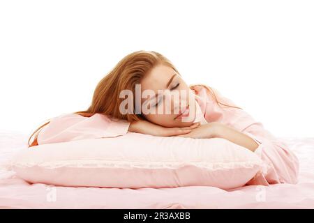 Young beautiful girl sleeps in the bed hugging a pillow on his stomach. Healthy sleep. Isolated on w Stock Photo