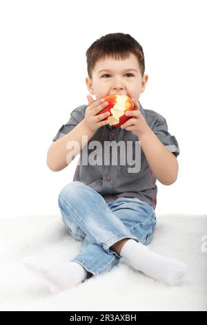 Little boy eating a red apple isolated on white background Stock Photo