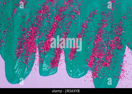 On a pink background, there are blue iridescent smudges of flowing acrylic paint with pink sparkles. Stock Photo