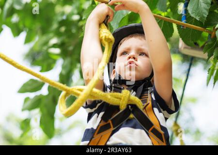 Girl climbing in adventure park is a place which can contain a wide variety of elements, such as rop Stock Photo