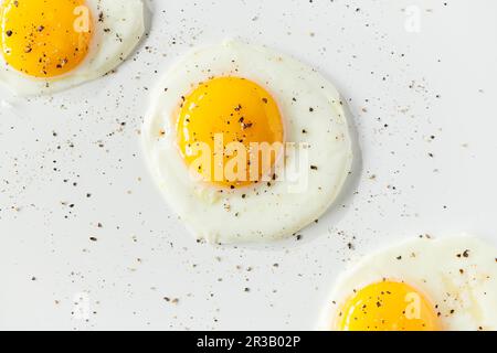 Three sunnyside eggs with pepper sprinkled over top Stock Photo