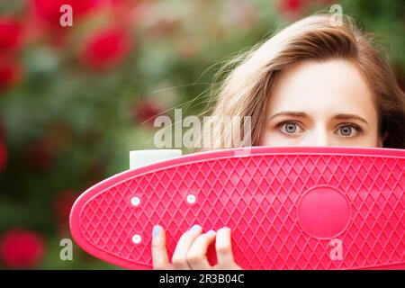 Lovely urban girl with a pink skateboard, close-up. Stock Photo
