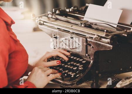 Secretary at old typewriter with telephone. Young woman using typewriter. Business concepts. Retro p Stock Photo
