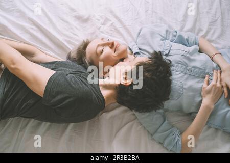 Man kissing woman lying on bed at home Stock Photo