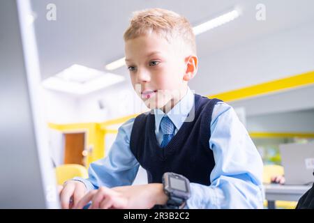 Concentrated boy using laptop in computer class Stock Photo