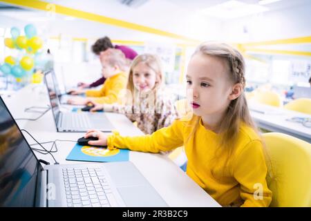 Girl using laptop sitting in computer class Stock Photo