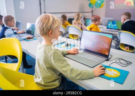 Boy studying through laptop sitting in computer class at school Stock Photo
