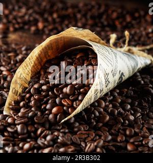 Black coffee beans studio shot. Freshly roasted coffee beans in a cone of paper Stock Photo