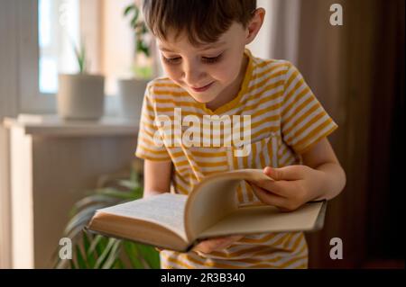 Smiling boy flipping pages of book at home Stock Photo