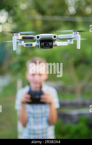 Kid flying drone.  Boy operate drones. Child Operating Quadcopter. Little Pilot Using Drone Remote C Stock Photo