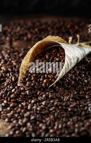Black coffee beans studio shot. Freshly roasted coffee beans in a cone of paper Stock Photo