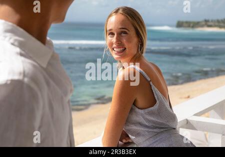 Happy woman leaning on railing and talking to man Stock Photo