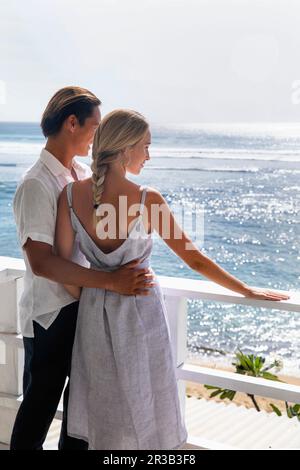 Young couple looking at sea standing by railing Stock Photo