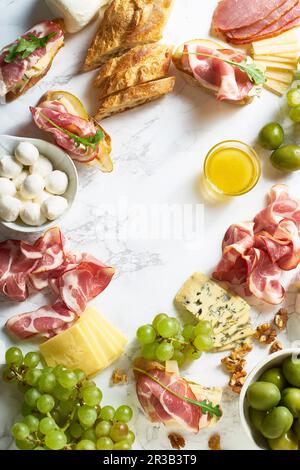 Cheese plate with brie, parmesan, cheddar and meat, fruits and baguette Stock Photo