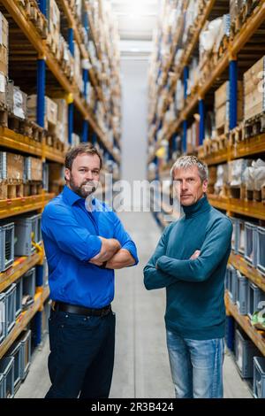 Mature businessmen standing with arms crossed in warehouse Stock Photo