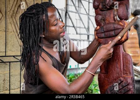 African Man sculptor carving a traditional statue out of wood Stock Photo