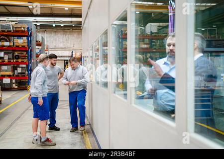 Colleagues talking to each other standing in production hall at factory Stock Photo