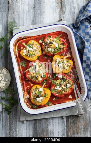 Peppers stuffed with rice, feta, mushrooms, dill and parsley in tomato sauce with feta cheese Stock Photo