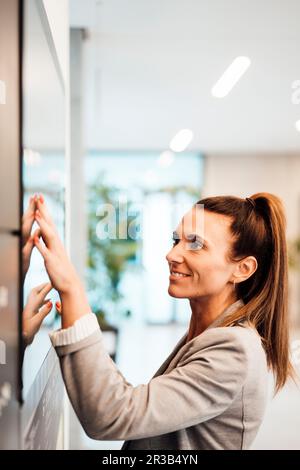 Smiling businesswoman touching display screen at office Stock Photo