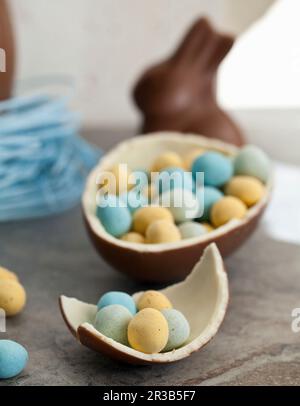 Easter chocolate egg in a blueberry candy nest, and a chocolate bunny, and a halved chocolate egg filled with mini chocolate eggs Stock Photo