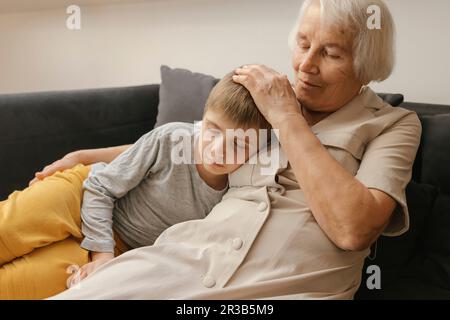 Boy relaxing by grandmother sitting on sofa at home Stock Photo