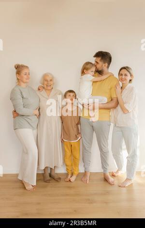 Happy multi-generation family standing together in front of wall at home Stock Photo