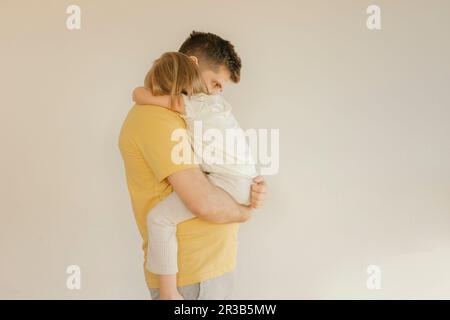 Father carrying daughter in front of wall Stock Photo