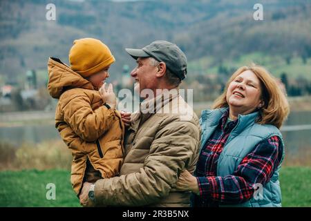 Grandparents having fun with grandson wearing warm clothing Stock Photo