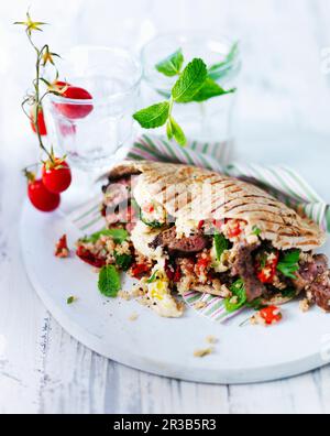 Pitta flatbread with lamb, mint, quinoa, hummus and red peppers Stock Photo