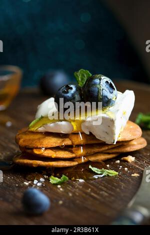 Camembert Cheese on savoury biscuits with honey and blueberries Stock Photo