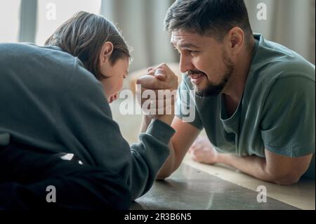 Father and son doing arm wrestling at home Stock Photo