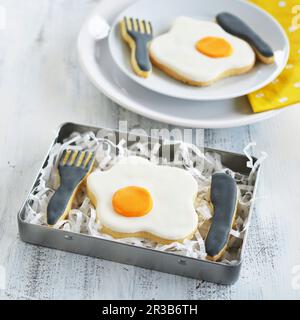 Fried egg and cutlery biscuits in a tin and on a plate Stock Photo