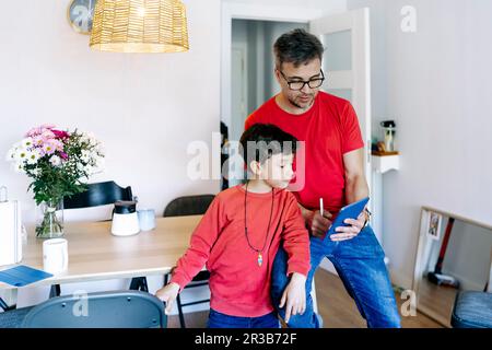 Son standing by father using tablet PC at home Stock Photo
