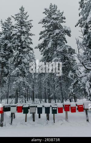Colorful mailboxes in front of snow covered trees Stock Photo