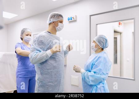 Doctor with colleagues preparing for surgery in operating room Stock Photo