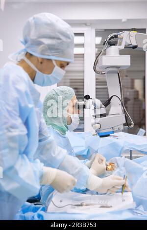 Nurse with doctor performing eye surgery in operating room Stock Photo