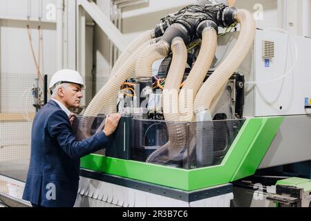Senior manager examining modern machine in factory Stock Photo