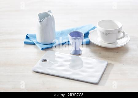 Studio shot of empty milk jug, cup, cutting board, napkin and eggcup Stock Photo