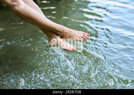 Woman with barefoot splashing water in lake Stock Photo
