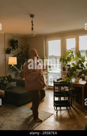 Carefree man dancing in living room Stock Photo