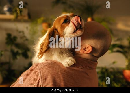 Bald man carrying dog on shoulder at home Stock Photo