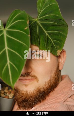 Young man with beard by plant leaf Stock Photo