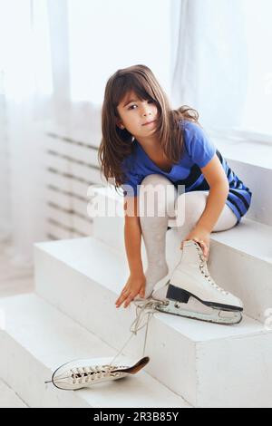 Little girl trying on a large ice skating. Little kid and skates Stock Photo