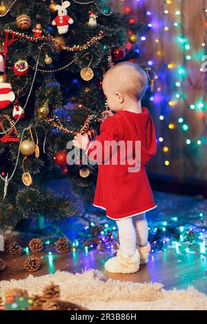 Little baby girl decorates the Christmas tree Stock Photo