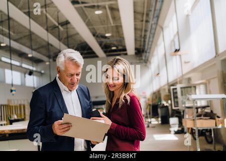 Businessman discussing with colleague over documents in factory Stock Photo