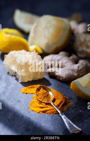 Lemon, turmeric powder, ginger, and honeycomb on a blue surface Stock Photo
