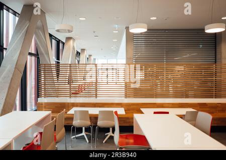 Empty chairs and tables arranged in modern illuminated building Stock Photo
