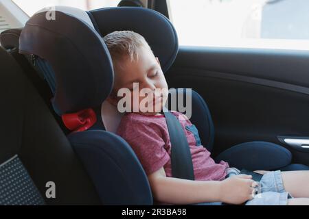 Boy sleeping on safety seat in car Stock Photo