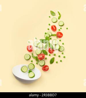 Fresh cut salad ingredients falling into white bowl Stock Photo